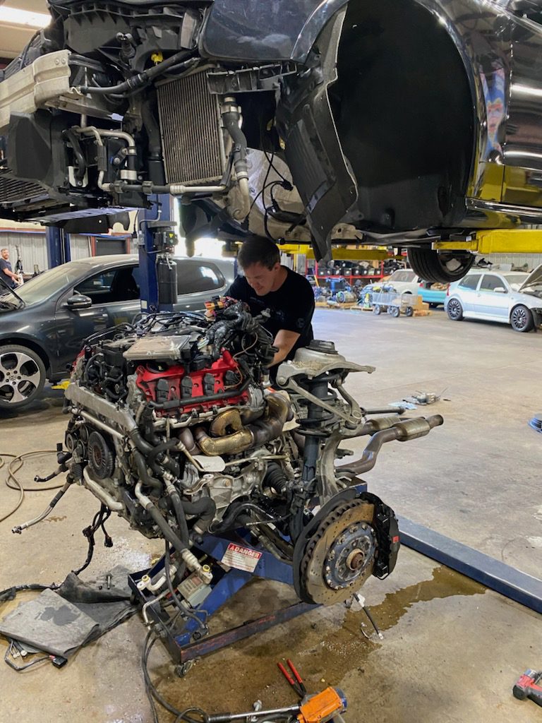 Mechanic working on Audi V8 engine during repair and replacement service.