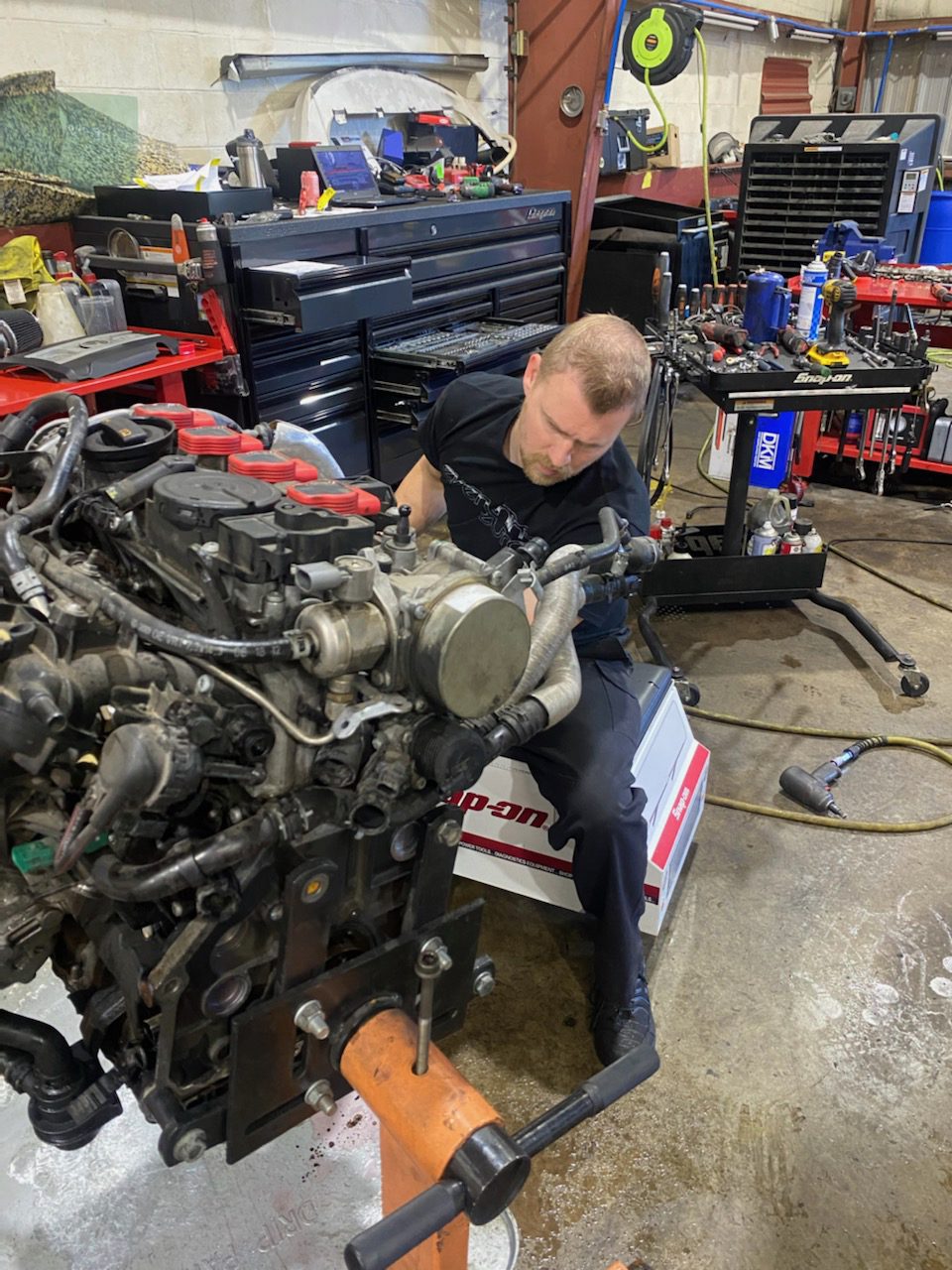 Mechanic working on car engine repair and replacement in a workshop.
