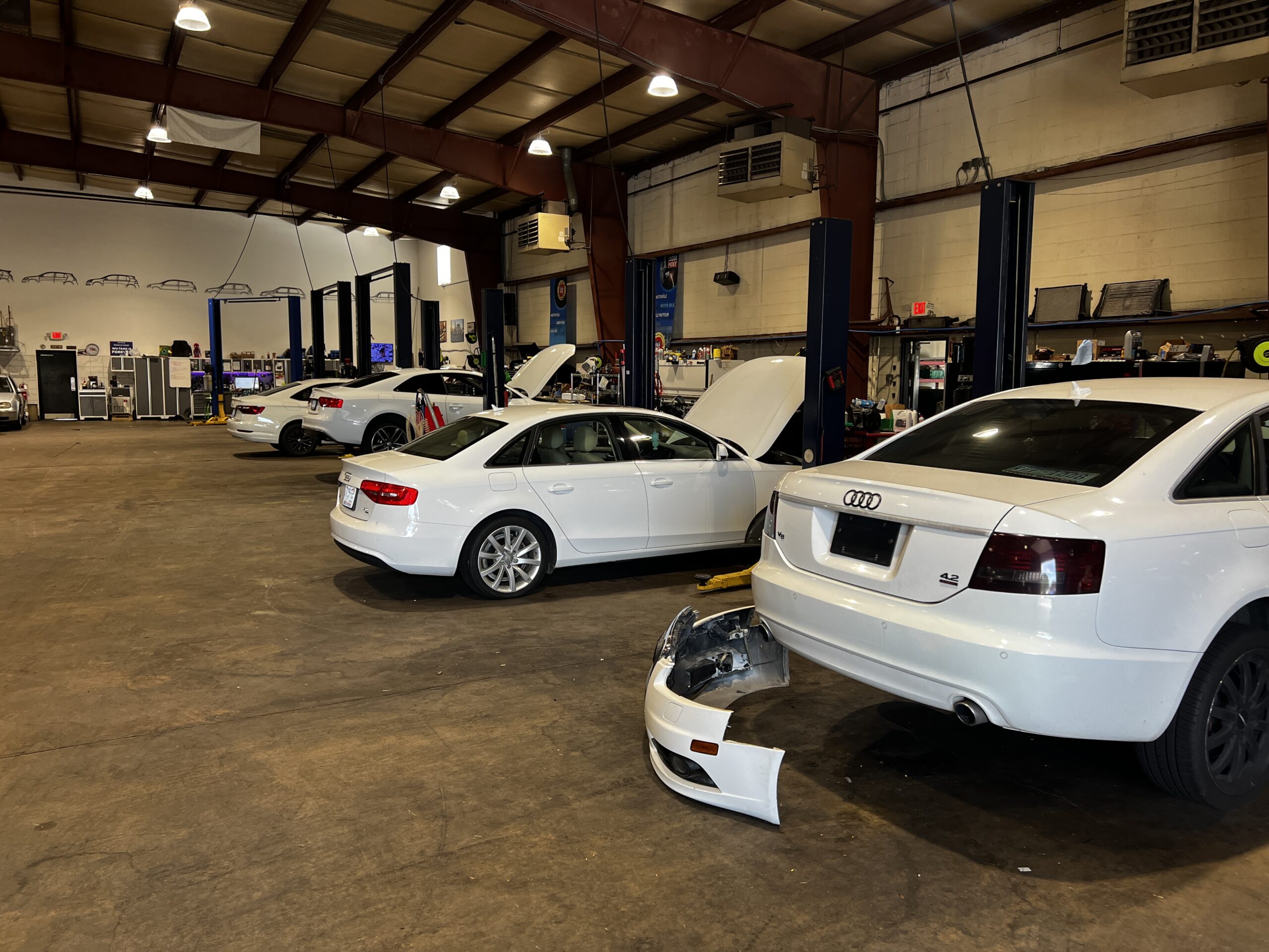 White Audi cars at Everything Euro Repair Shop, one with bumper removed.