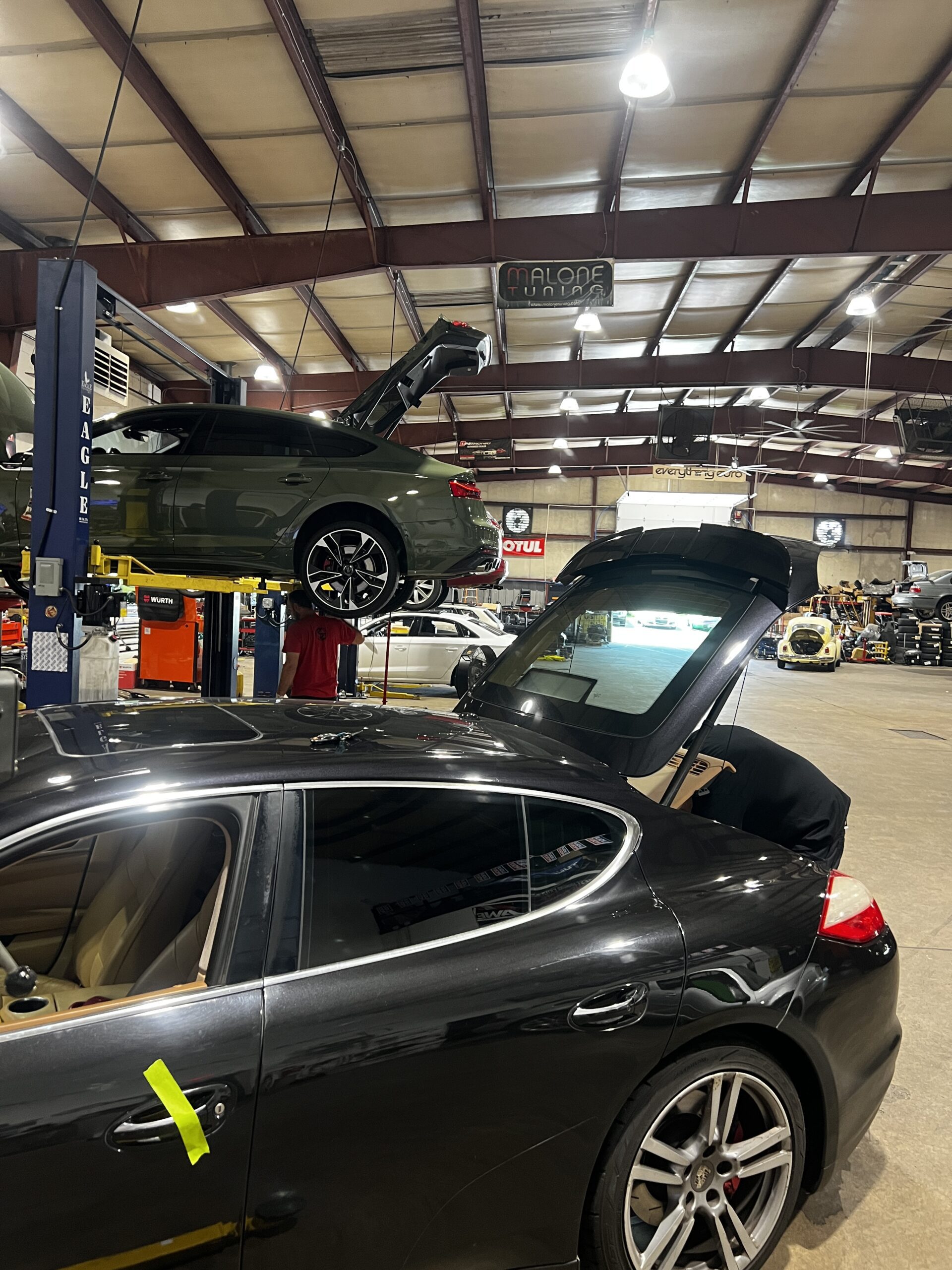 Euro repair shop: two luxury cars on lifts with open trunks