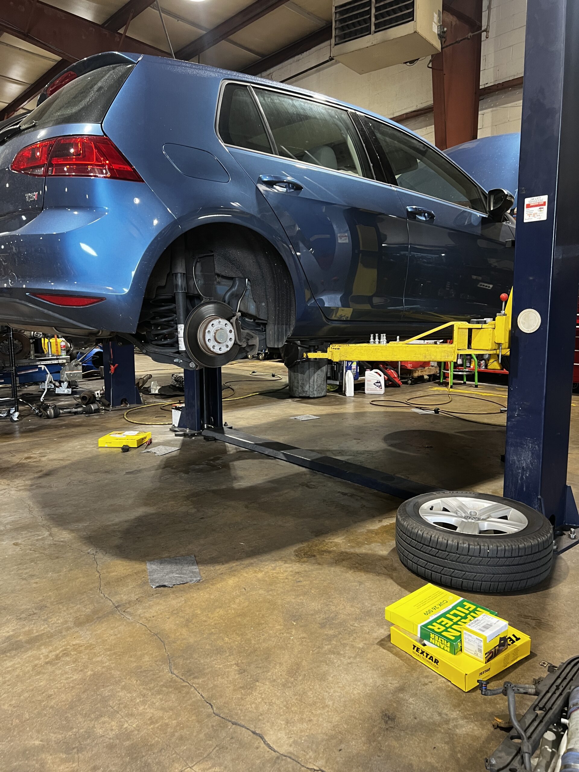 Blue Volkswagen Golf on a car lift at a Euro repair shop, with new oil filter box.