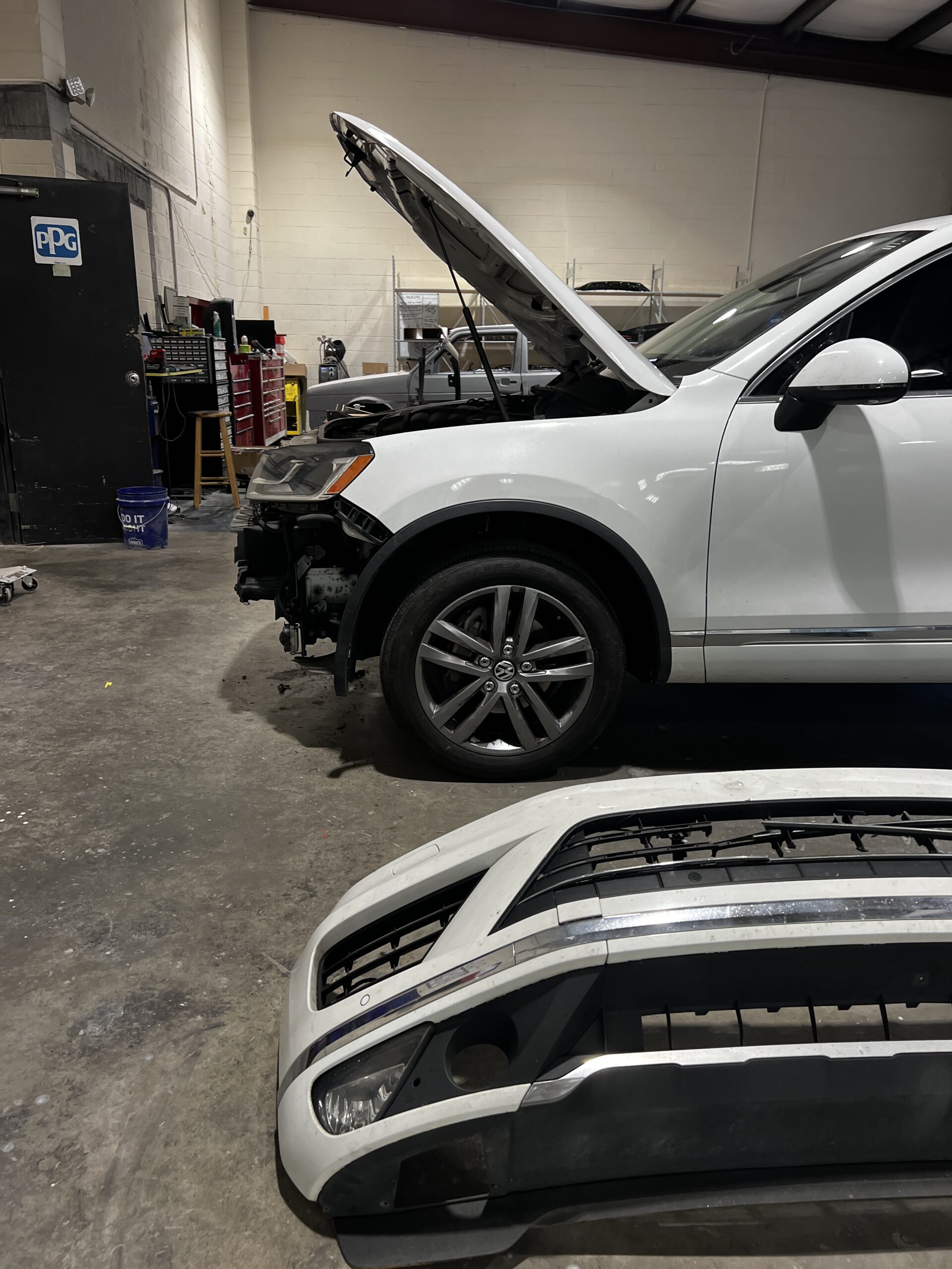 Euro repair shop: White Volkswagen SUV with front bumper removed for auto repair.